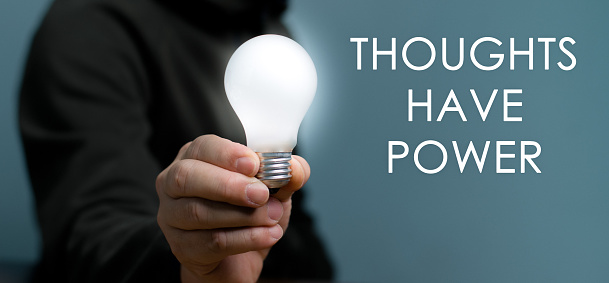 Hand holding light bulb with text Thoughts Have Power, The power of thinking ideas, think big.