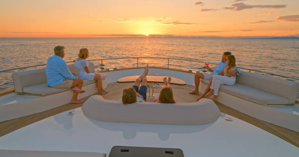 Family relaxing on yacht Family looking at view while sitting on sofa in luxury yacht. big family sunset stock pictures, royalty-free photos & images