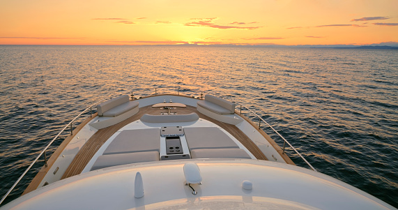 Modern yacht cruising in sea during sunset.