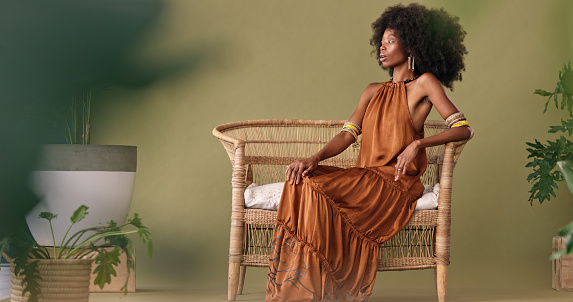 African, fashion and black woman in tropical studio design to model interior design, furniture and plants on green background. Afro woman sitting on chair mockup for beauty, natural skin and wellness