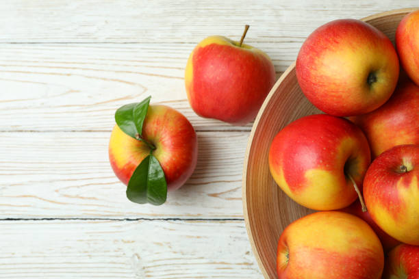 istock Bowl with red apples on white wooden table 1436083068