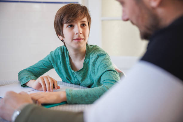 Preadolescent boy looking at his father, learning at home together