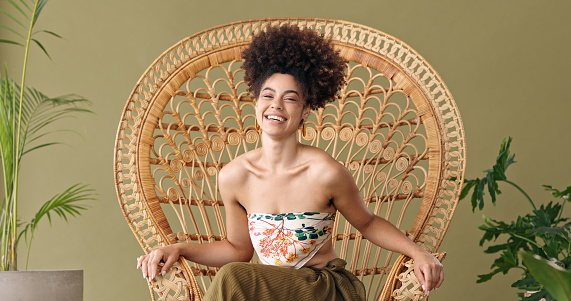 Afro portrait and black woman on wicker furniture enjoying leisure rest with cheerful smile. Happy, relaxed and calm african american girl with natural hair relaxing on a woven armchair.