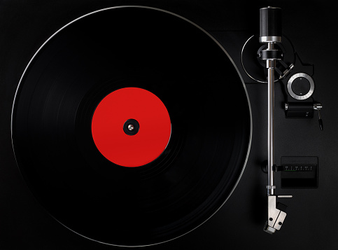 Black turntable playing vinyl record, blank label. Top view of old fashioned turntable.