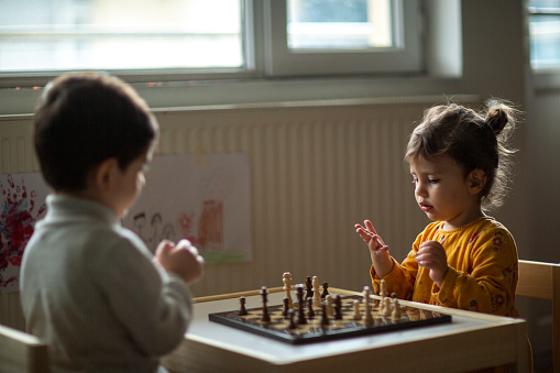 Little girl playing chess with her brother