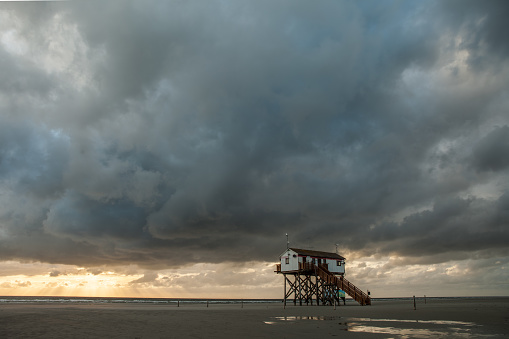 Stilt houses in St. Peter-Ording with dramatic clouds.