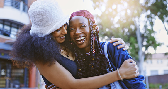 Happy, love and black lgbtq couple hugging outdoors while on a walk in the city for fresh air. Happiness, smile and trendy lesbian african women embracing and bonding together in an urban town.