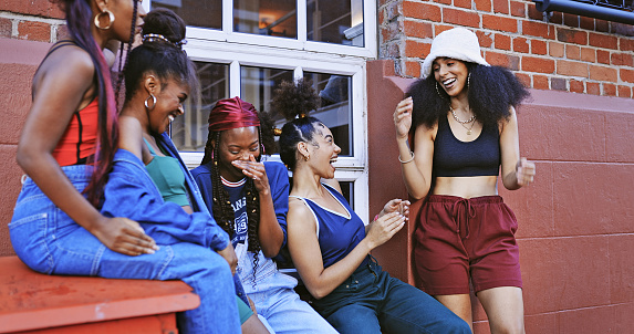 Black women, laughing friends and street style fashion with cool comic attitude against an urban city building talking and having fun. Beautiful and funny females outdoor looking trendy in Florida