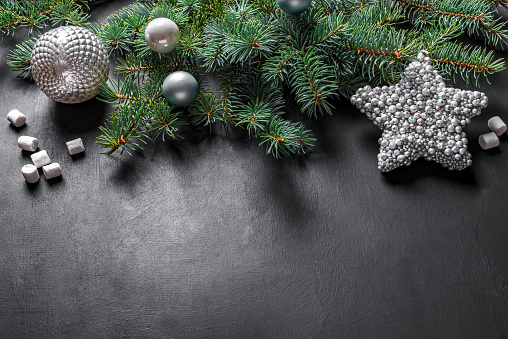 Christmas composition. Christmas decor, pine cones, fir branches, silver star and ornaments on black background, top view, copy space.