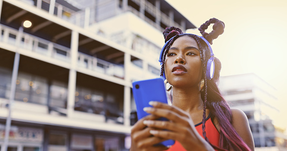 Gen z woman, music phone and city street fashion, trendy style and cool attitude influencer. Hipster black girl listening to audio with headphones, social media apps and unique urban youth lifestyle