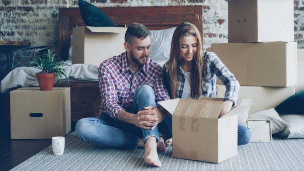 istock Excited young couple is unpacking things, opening box, taking personal items and talking after moving to new apartment. Relationship and relocation concept. 1436109301