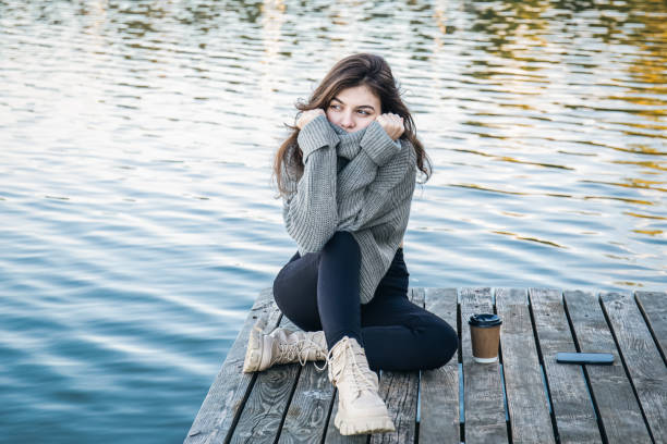 istock An attractive young woman in a sweater sits by the river. 1436110511
