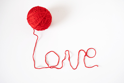 The word Love is lined with a thread from a ball of red color.