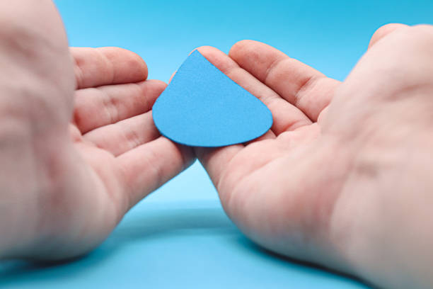 istock Hands holding a paper water drop on a blue background. Concept save water, drought, world water day, hand sanitizer and hygiene, family washing hands, CSR, save water, clean renewable energy drop 1436112287