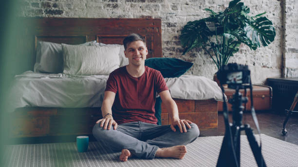 istock Handsome young man blogger is recording video for his subscribers talking and gesturing using professional camera on tripod. Social media and modern technology concept. 1436115759