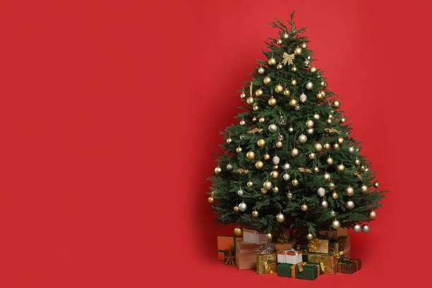 istock Beautifully decorated Christmas tree and many gift boxes on red background, space for text 1436115797