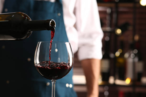 bartender pouring red wine into glass indoors, closeup. space for text - wine bottle imagens e fotografias de stock