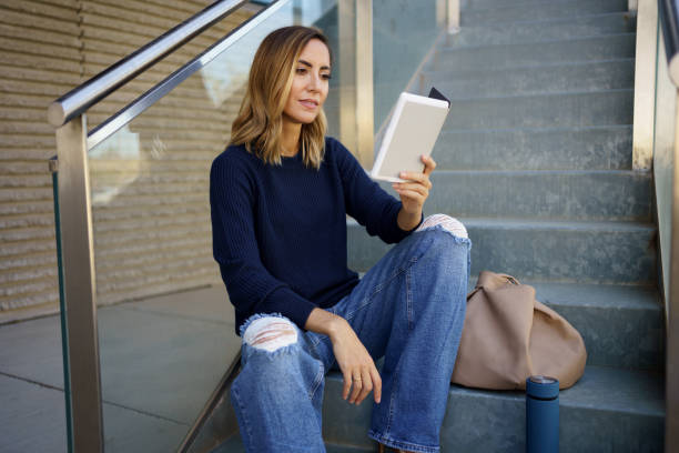 istock Middle-aged woman reading with her e-book on a coffee break near her office. 1436116508