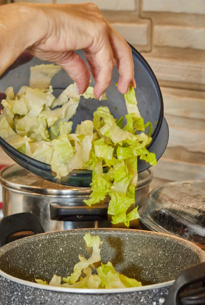 istock Chef is throwing lettuce in pot on gas stove 1436118090