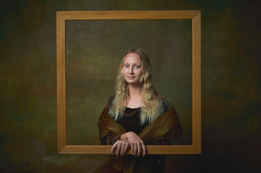 Art gallery. Vintage style portrait of young charming girl in image of Mona Lisa, La Gioconda isolated on dark green background. Concept of modern art, beauty, style, imitation and aspiration