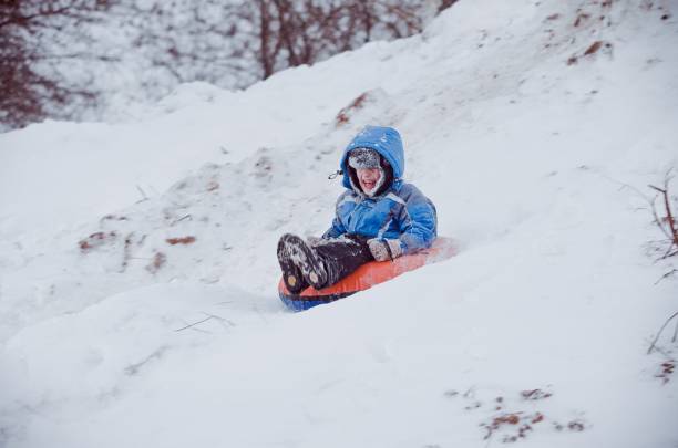 istock Boy sliding down hill on a snow tube 1436120157
