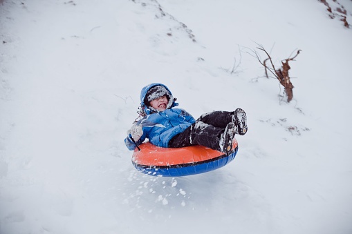 Cute child boy riding on snow tubing. Winter fun activity outdoor. Winter vacation: riding on snow tubings