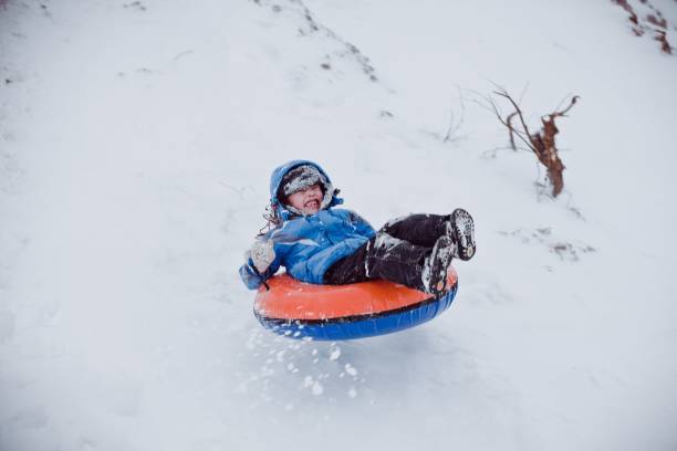 Boy sliding down hill on a snow tube stock photo