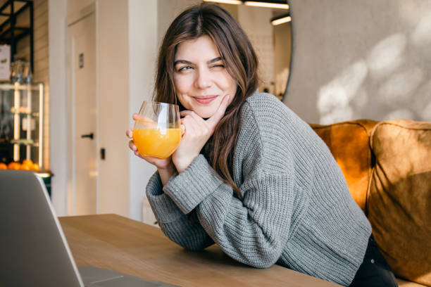 jolie jeune femme avec un verre de jus d’orange fraîchement pressé. - juice drinking women drink photos et images de collection