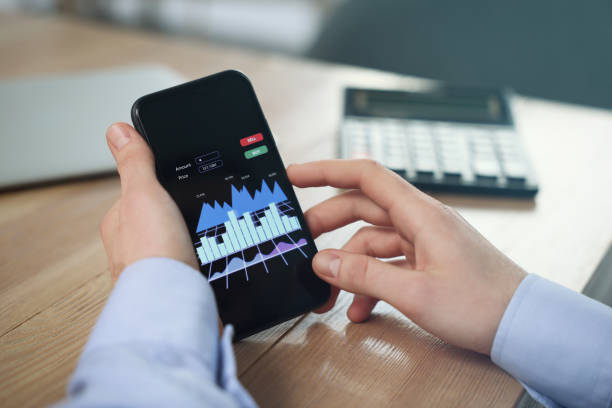 istock Forex trader with smartphone working at wooden table, closeup 1436123317