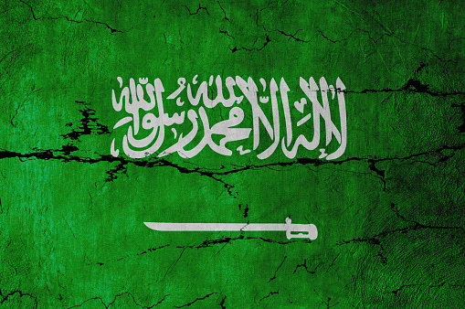 Saudi Arabian Flag on cracked wall background.