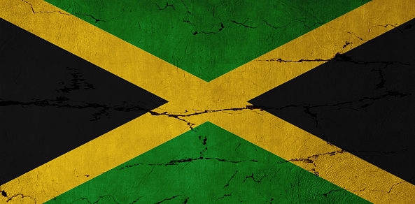 Jamaican Flag on cracked wall background.