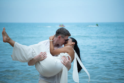 Interracial couple with the joy of traveling to the beautiful blue sea like the paradise of the Asian Sea.