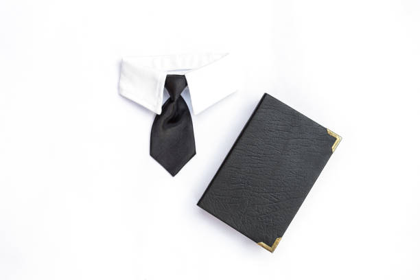 Black necktie and book with black leather cover isolate on white background, business concept