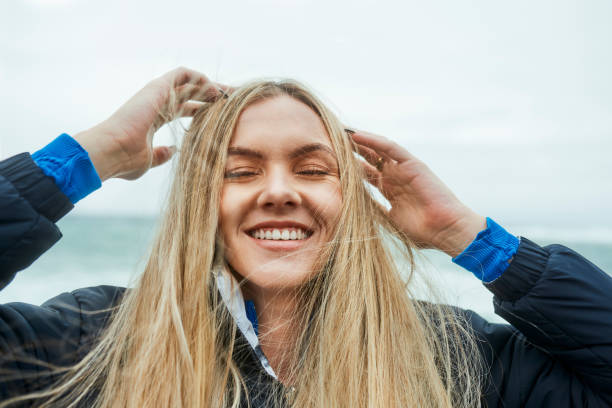 paz, cabelo e mulher calma com liberdade sentindo-se feliz, relaxar e desfrutar do dia ao ar livre por água, oceano ou mar. natureza, sorriso e bem-estar para a jovem geração z menina no canadá para férias, viagens ou férias - real people - fotografias e filmes do acervo