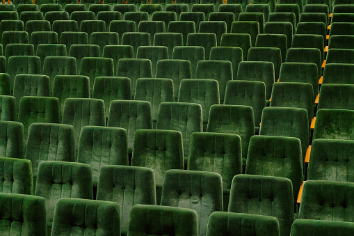 Rows of green seats in empty assembly hall for performance