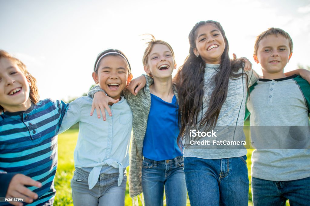 Elementary Friends Outdoors A small group of Elementary children huddle in closely to one another as they pose for a portrait.  They are each dressed casually and are smiling as they spend the time together. 10-11 Years Stock Photo