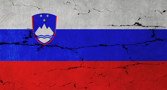 Slovenian Flag on cracked wall background.