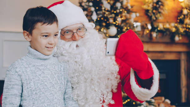 istock Santa and little boy making video call online using modern smartphone talking indoors 1436144295