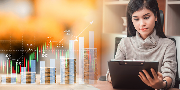 businesswoman working market analysis at office with step of coins and growing income graph, financial and investment, Invest, income, banking and profit concept.