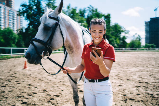 istock Horsewoman with smartphone walking stallion 1436145542