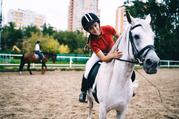 istock Female equestrian in black helmet caressing horse in paddock 1436145622