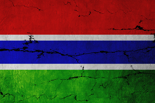 Gambian Flag on cracked wall background.