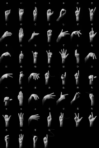 Dramatic B&W image of male hands demonstrating Japanese sign language fingerspelling full alphabet with text description
