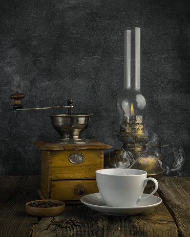 Antique coffee grinder with steaming coffee, and coffee beans. still life