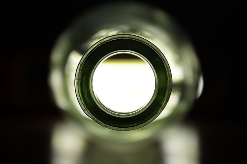A selective closeup of a hole of a bottle neck in the darkness
