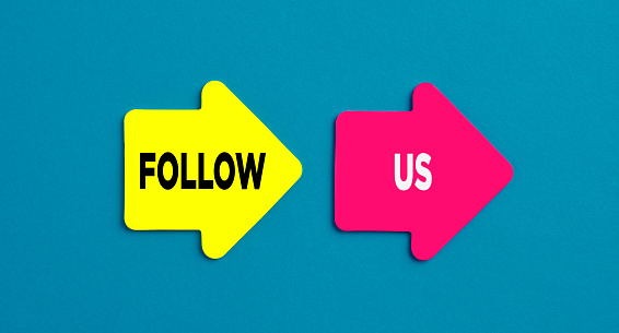 Follow us concept. The word follow us on arrow shaped stickers on blue background.