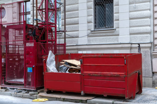 istock Red metal dumpster container full of construction garbage near freight construction elevator, house renovation. 1436152084