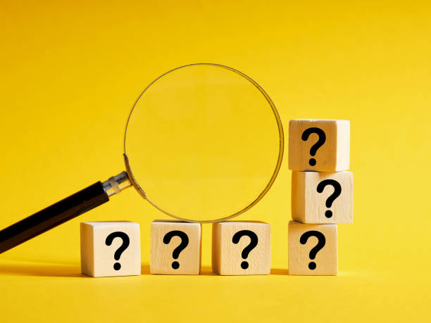istock Magnifying glass with wooden cubes with question marks. 1436152378