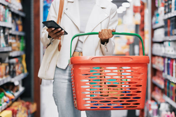 compras de supermercado, varejo e mulher negra com telefone na loja, loja ou supermercado. garota comprando mantimentos ou comprando produtos em um mercado de comida ou outlet enquanto envia mensagens de texto no celular ou smartphone. - lista de compras - fotografias e filmes do acervo