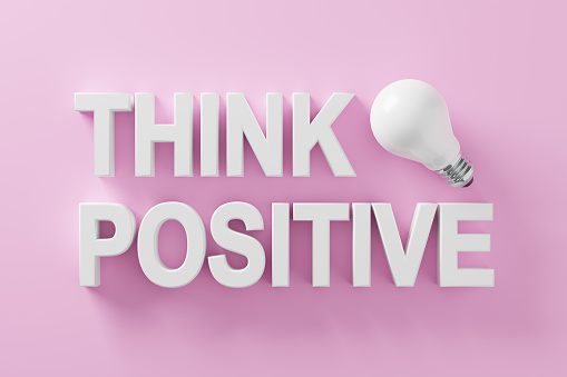Positive thinking and optimism in business or life concept. The word think positive with an idea light bulb on pink background. 3D rendering.